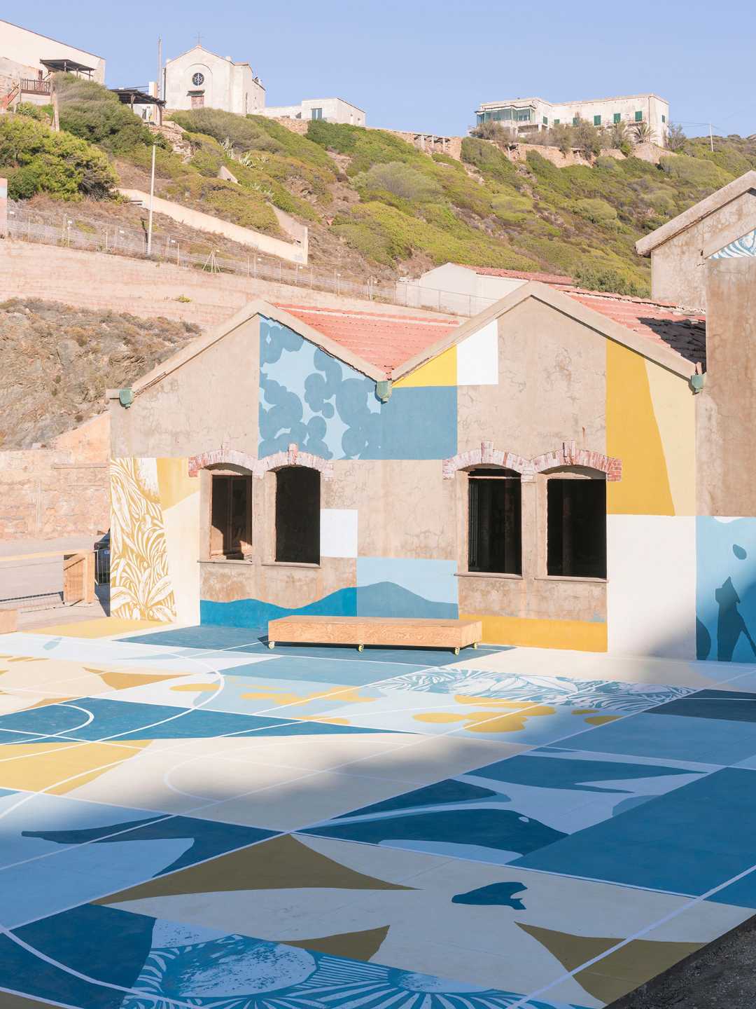 Vista d'insieme di Fronte Mare all'Argentiera, con l'ex edificio minerario dipinto e la pavimentazione a mosaico geometrico