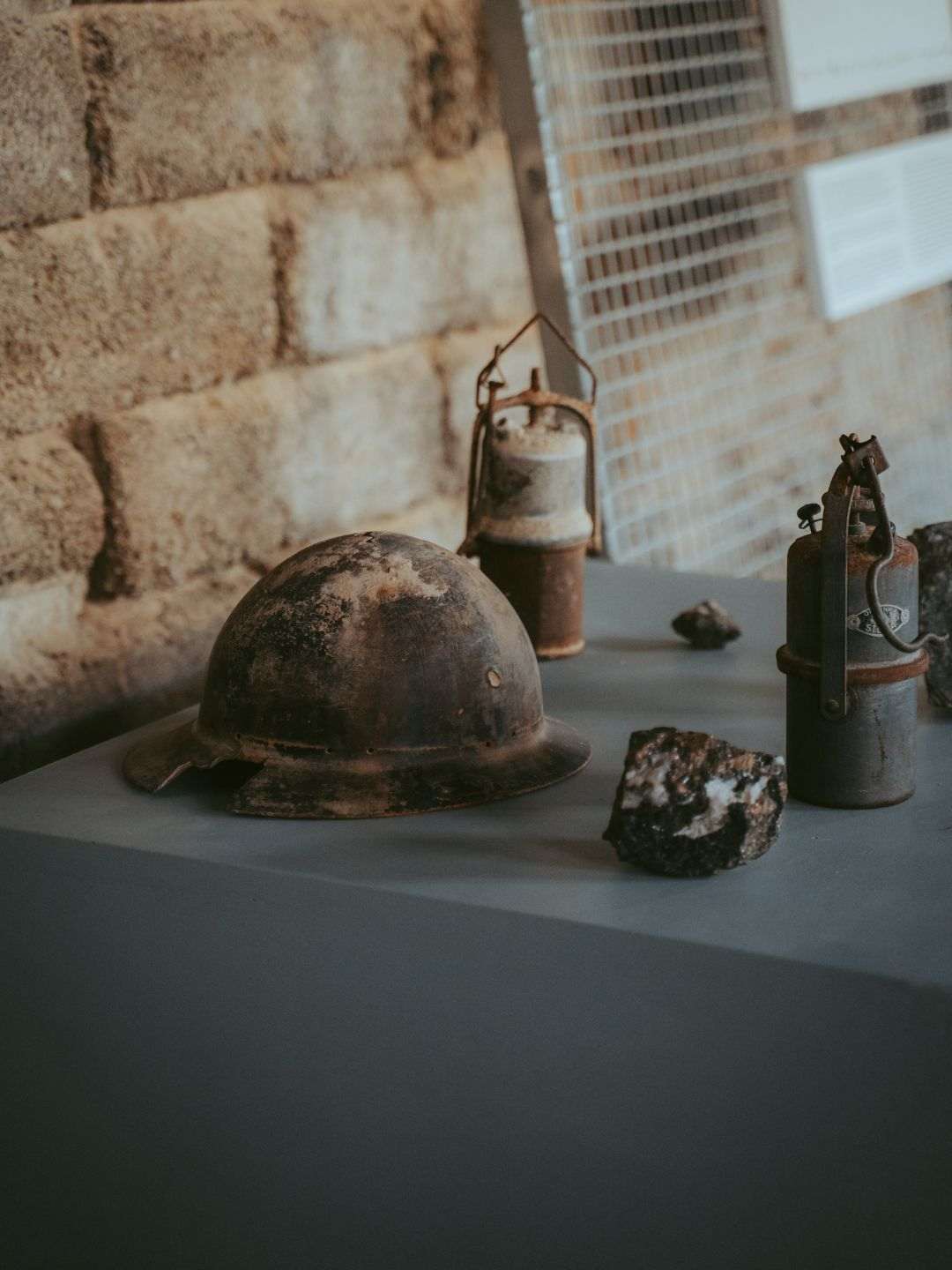 Un casco, lampade e un frammento di minerale grezzo esposti tra gli attrezzi da minatore dell'Argentiera