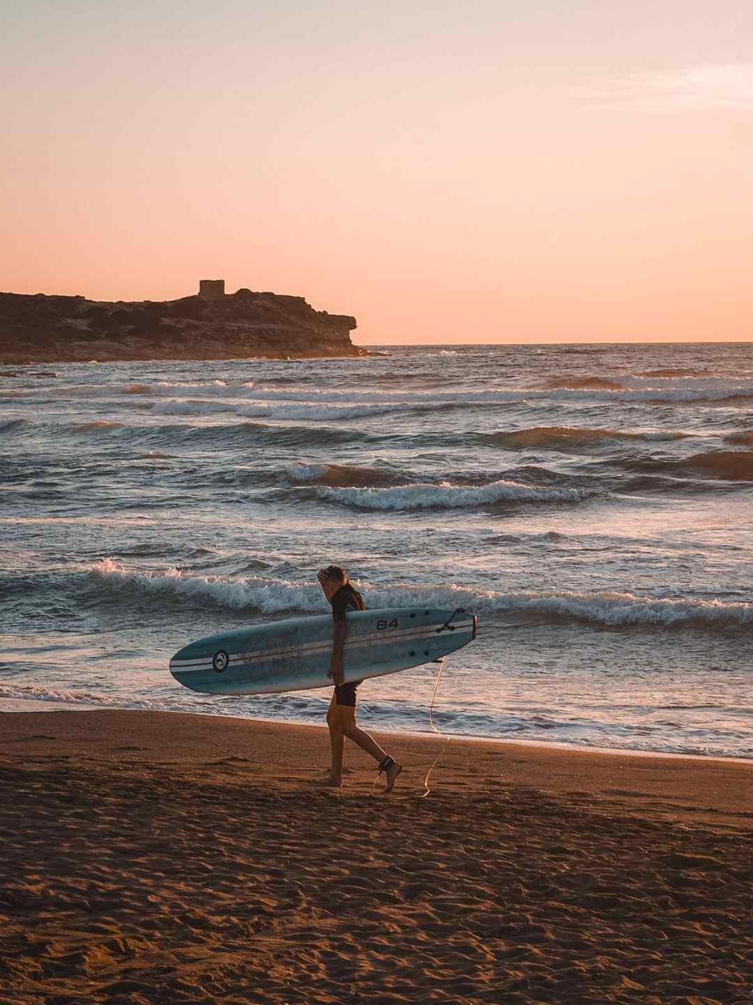 Surfista cammina sulla spiaggia di Porto Ferro