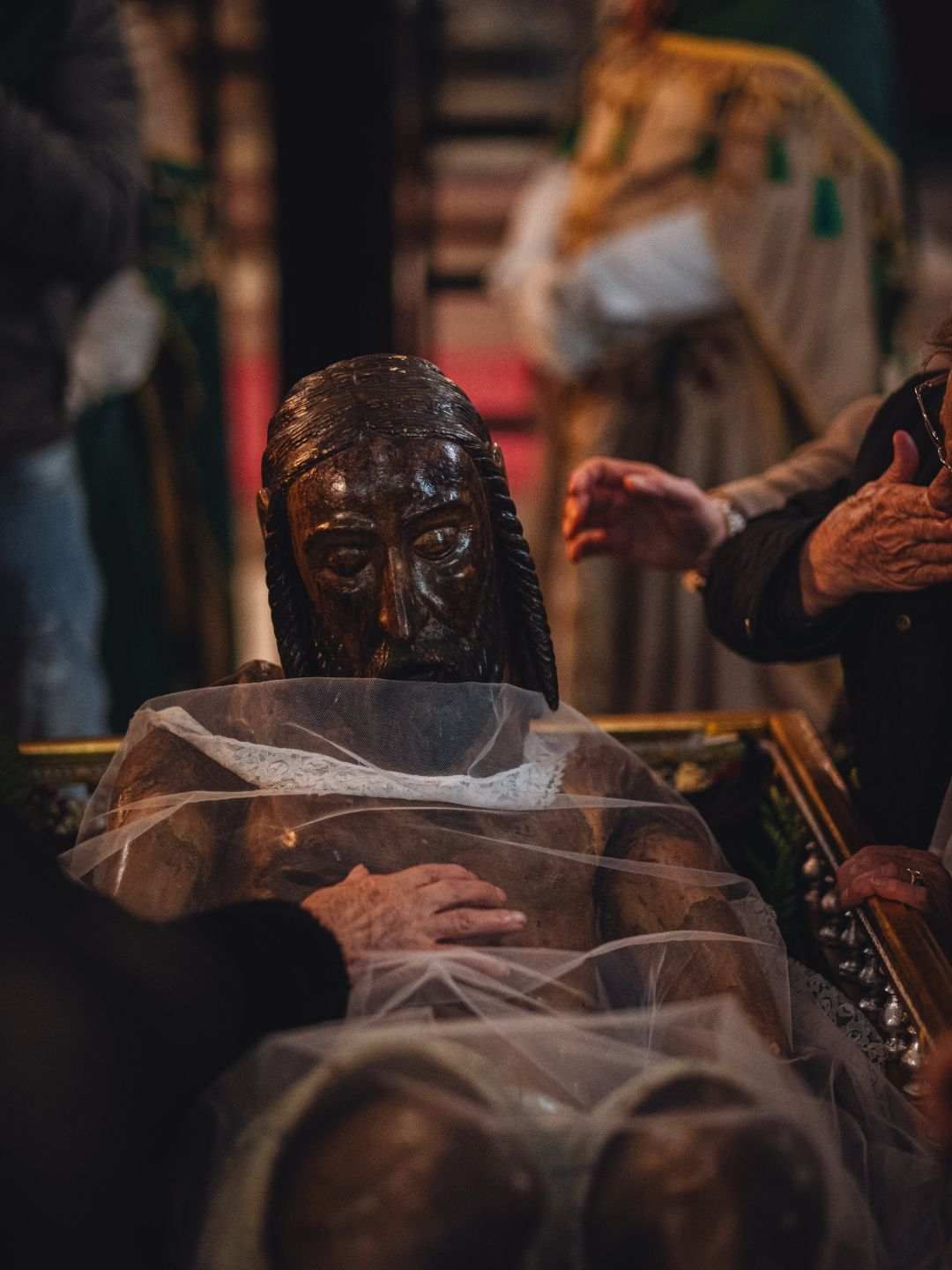Signore toccano il Cristo sceso dalla Croce durante la Settimana Santa a Sassari